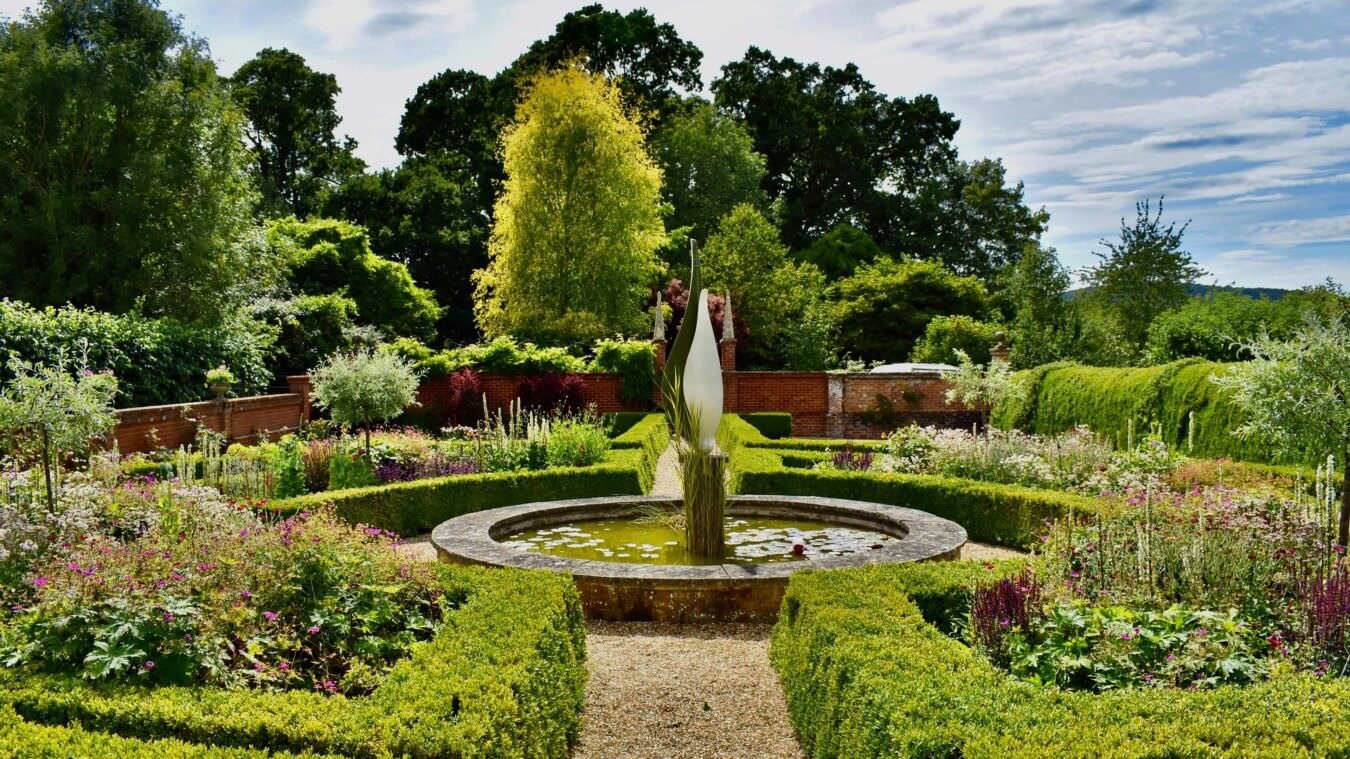 Formal gardens at Bignor Park featuring a central fountain, clipped box hedging and colourful seasonal planting