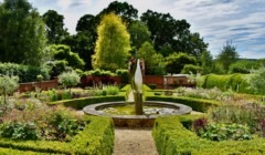 Formal gardens at Bignor Park featuring a central fountain, clipped box hedging and colourful seasonal planting