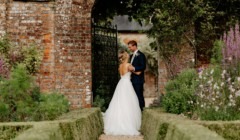 Bride and groom portrait in walled gardens at Bignor Park West Sussex with brick archway and romantic outdoor wedding setting