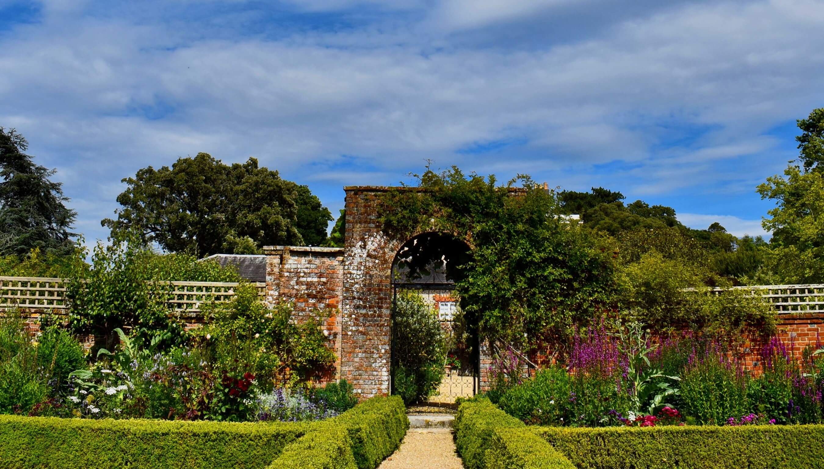 Walled garden at Bignor Park West Sussex with brick archway, manicured hedges and colourful flowers ideal for outdoor wedding photography