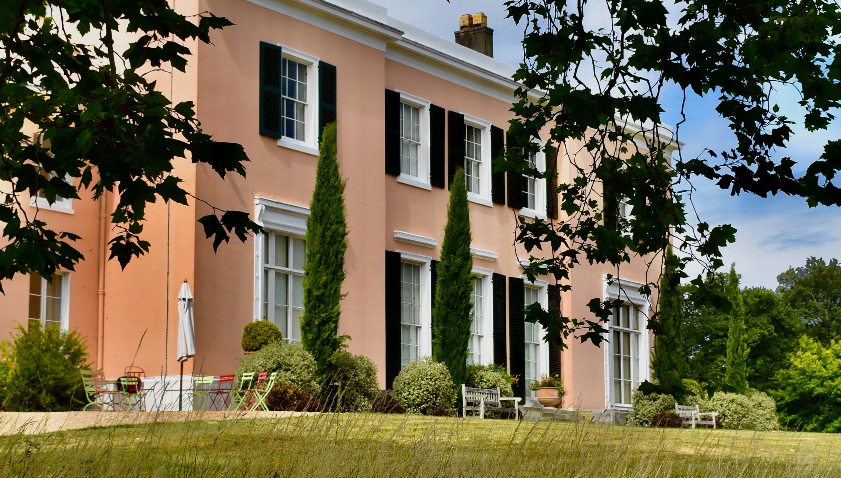 Bignor Park Georgian house exterior West Sussex with pastel façade, shuttered windows and landscaped gardens wedding venue setting