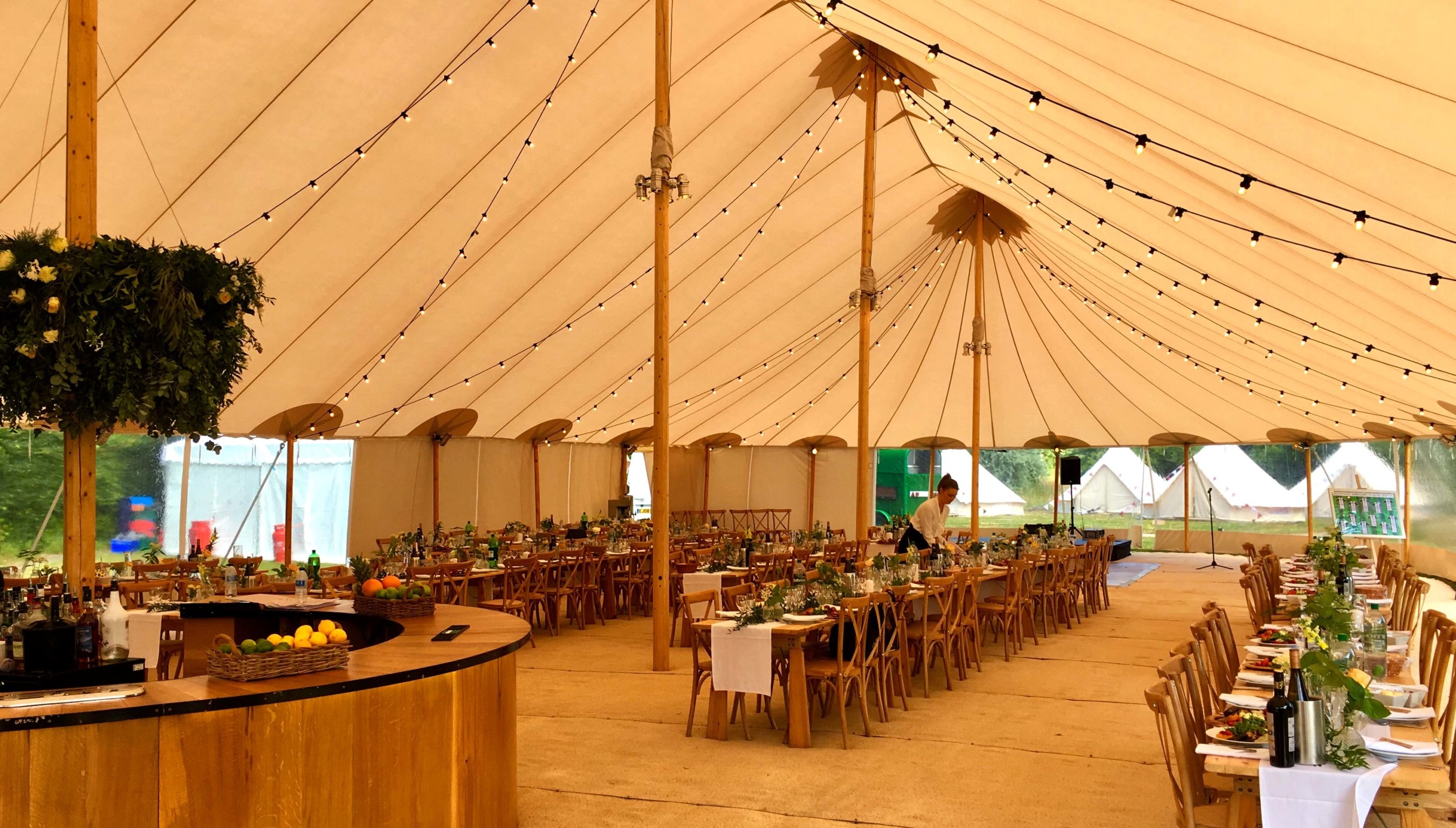 Wedding reception marquee at Bignor Park in West Sussex with elegant table settings and festoon lighting