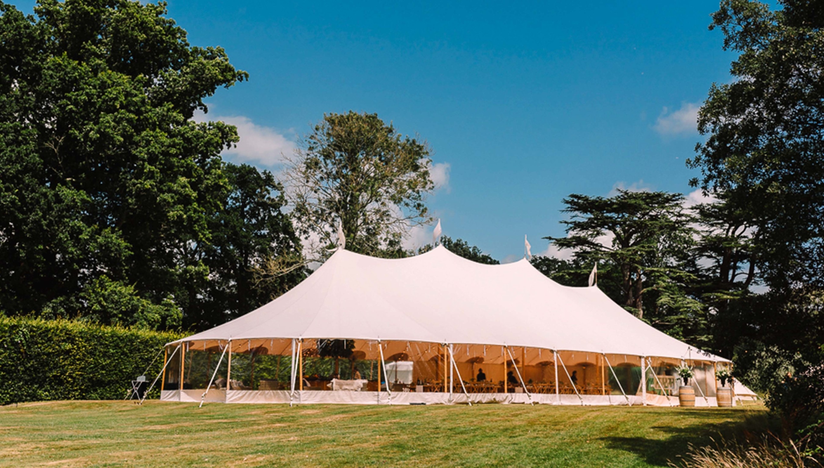 Outdoor wedding marquee at Bignor Park in West Sussex set on lawn surrounded by trees