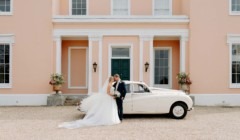 Wedding couple in front of Bignor Park country house in West Sussex with vintage car
