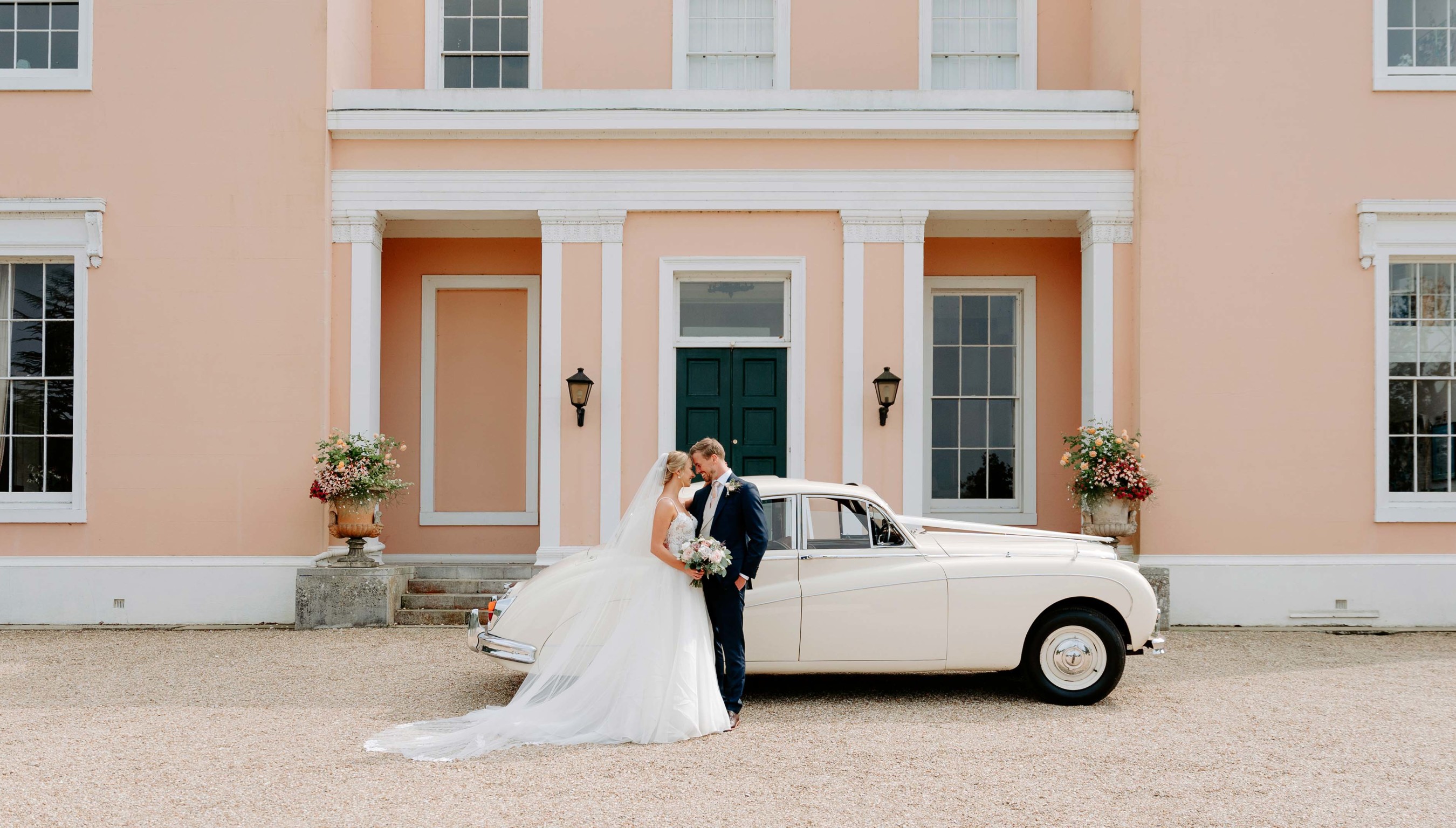 Wedding couple in front of Bignor Park country house in West Sussex with vintage car