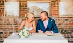 Outdoor wedding, Signing the register together, sharing a quiet, joyful moment just after saying “I do” at Bignor Park's Greek Loggia