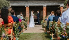 Outdoor wedding ceremony at the Greek Loggia at Bignor Park Sussex with guests seated outdoors