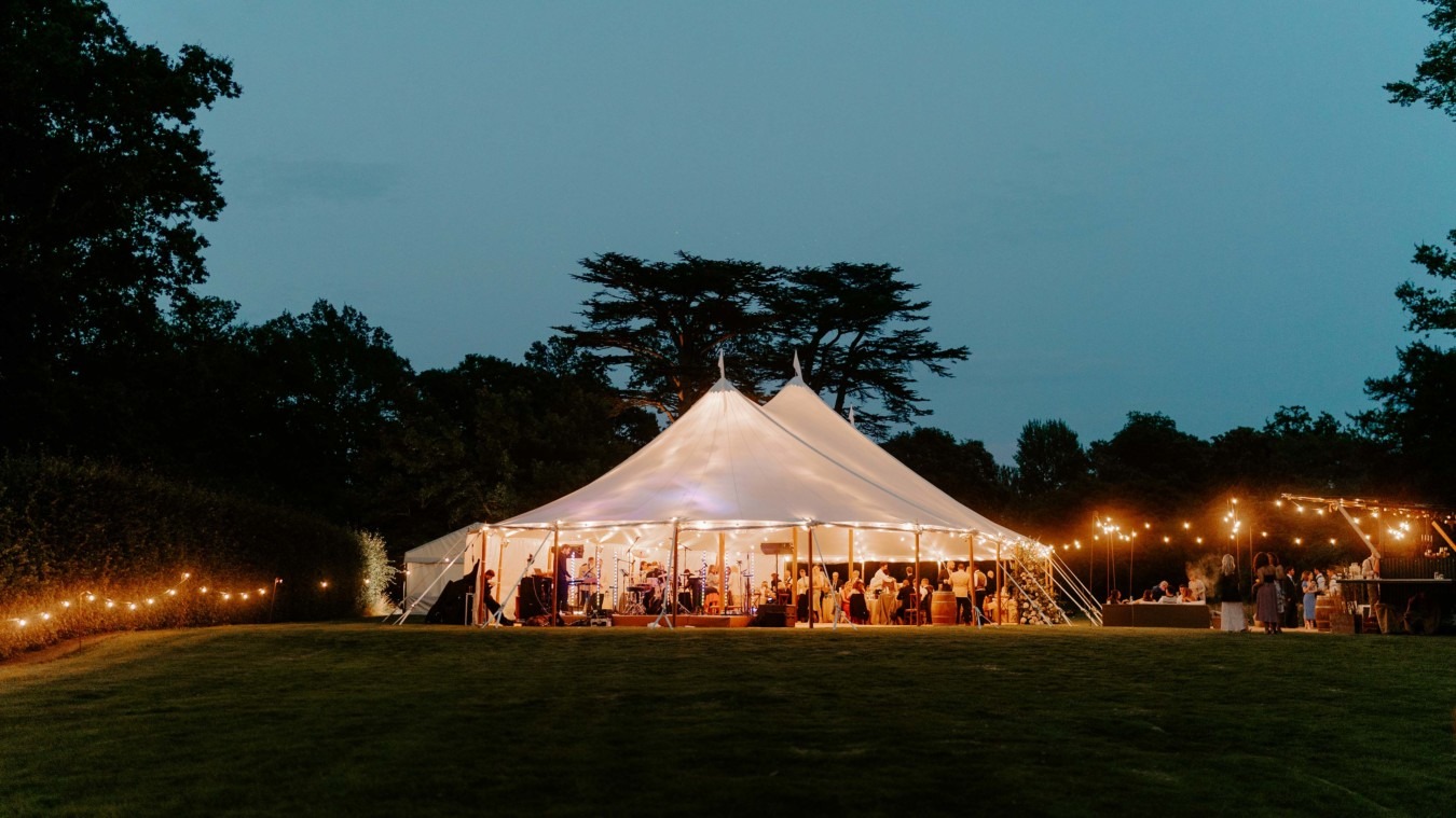 Evening wedding reception marquee at Bignor Park in West Sussex, illuminated with festoon lights in a romantic countryside setting