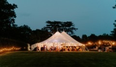 Evening wedding reception marquee at Bignor Park in West Sussex, illuminated with festoon lights in a romantic countryside setting