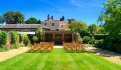 Outdoor wedding ceremony setup at the Greek Loggia at Bignor Park in West Sussex with garden seating