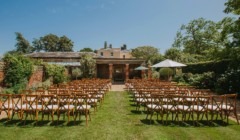Large outdoor wedding ceremony setup at Bignor Park Greek Loggia in West Sussex with chairs on lawn