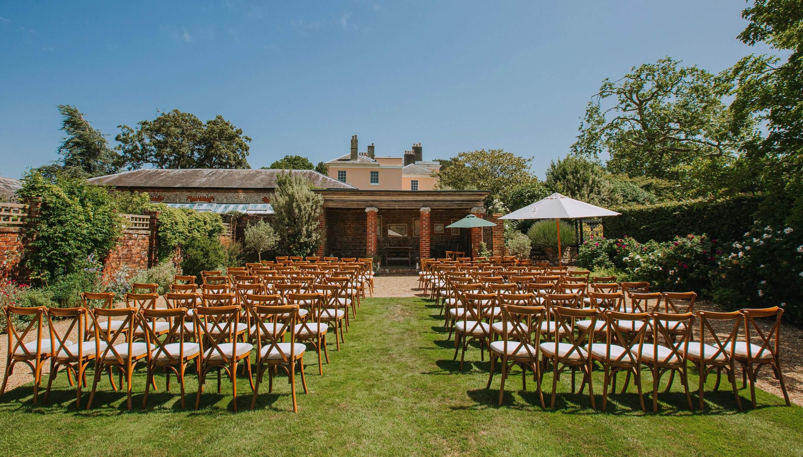 Large outdoor wedding ceremony setup at Bignor Park Greek Loggia in West Sussex with chairs on lawn