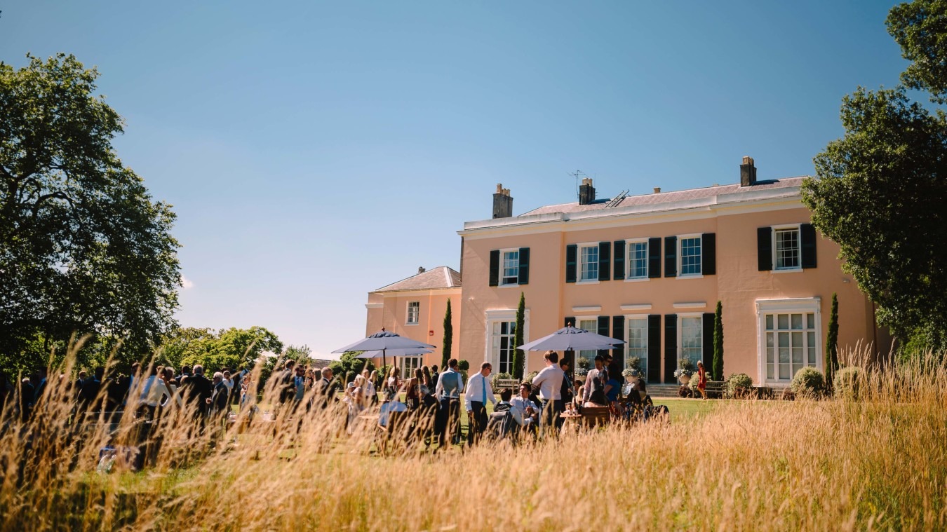 Wedding drinks reception at Bignor Park in West Sussex with guests on the South lawn outside the country house