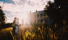 Bride and groom embracing at sunset in front of Bignor Park house in West Sussex, surrounded by wild meadow grass