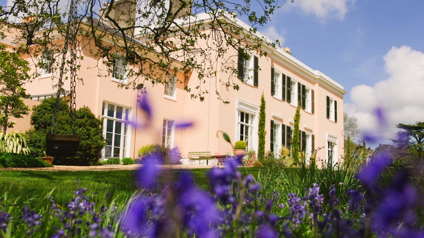 Bignor Park country house exterior in West Sussex with bluebells in foreground on a sunny day