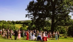 Wedding guests gathered on South Lawn at Bignor Park with panoramic countryside views and mature trees