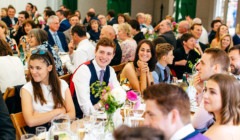 Wedding guests enjoying speeches during wedding breakfast in the stables at Bignor Park in West Sussex