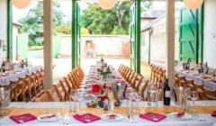 A set up for a wedding breakfast with the green stables doors open and looking out to the quadrangle at Bignor Park