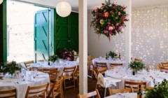 Bignor Park wedding reception in The Stables with round tables, fairy lights backdrop and hanging floral arrangement West Sussex venue