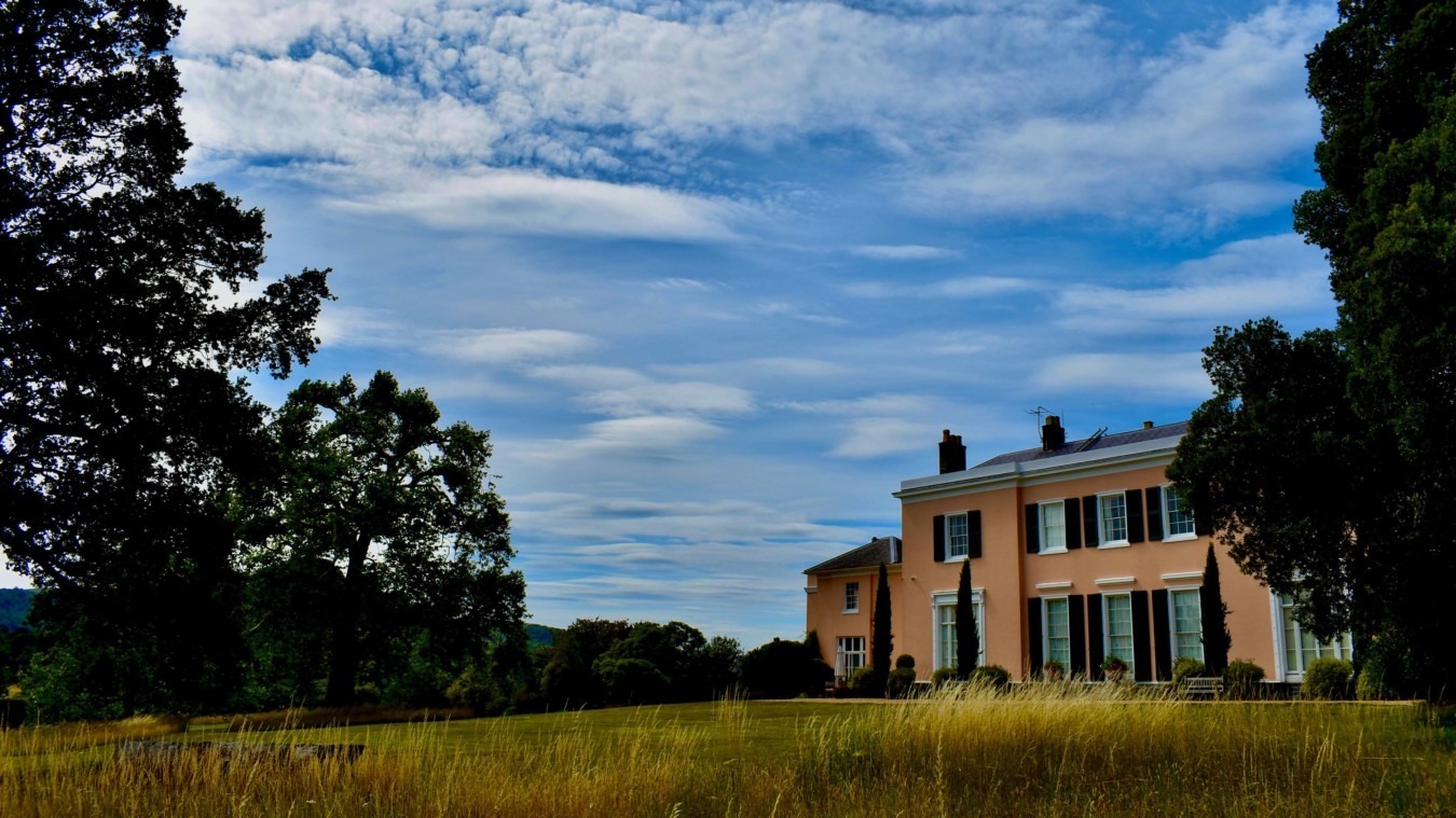 Bignor Park West Sussex wedding venue house and grounds with rolling lawn, mature trees and dramatic sky perfect for outdoor ceremonies