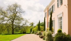 Outdoor wedding venue Bignor Park Georgian country house exterior in West Sussex with landscaped gardens, gravel terrace and mature trees in soft sunlight