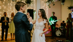 Bride and groom sharing their first dance at a Bignor Park wedding reception, with live band and fairy lights creating a warm, intimate atmosphere in The Stables