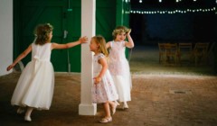 Bridesmaids playing during wedding reception in the stables courtyard at Bignor Park in West Sussex with festoon lighting