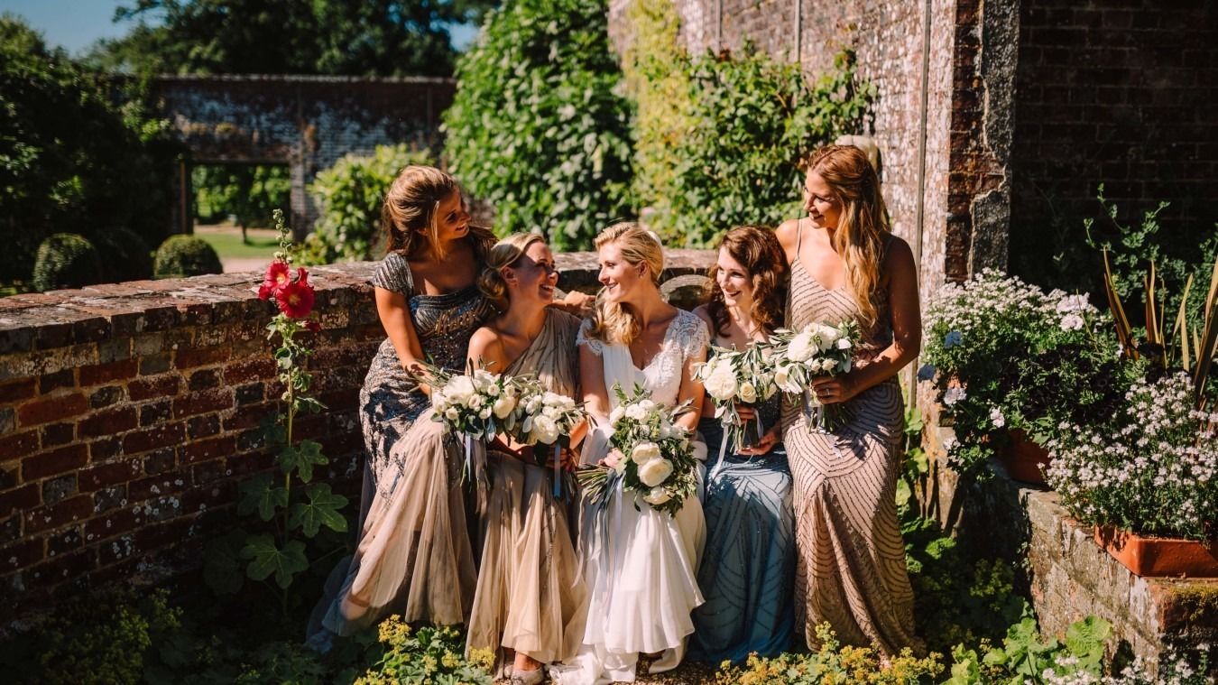 Bride and her bridesmaids having a quiet moment together in Bignor Parks ornamental gardens