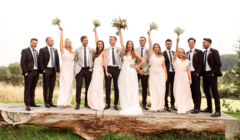 Best men and Bridesmaids raising bouquets standing on the tree table on the South lawn of Bignor Park during an outdoor wedding
