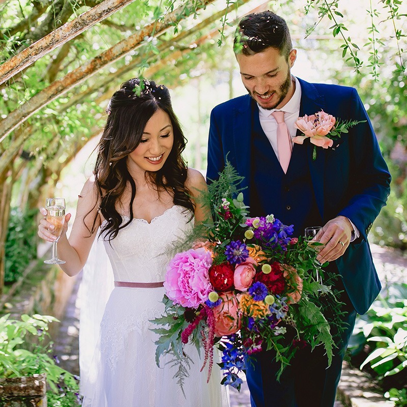 Outdoor wedding at Bignor Park with bride and groom in romantic garden setting surrounded by greenery and flowers