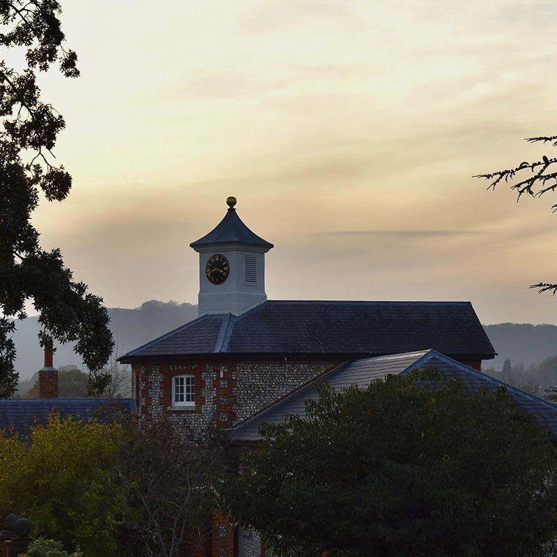 Evening light over Bignor Park’s historic stables, with the clock tower silhouetted against a soft West Sussex sunset